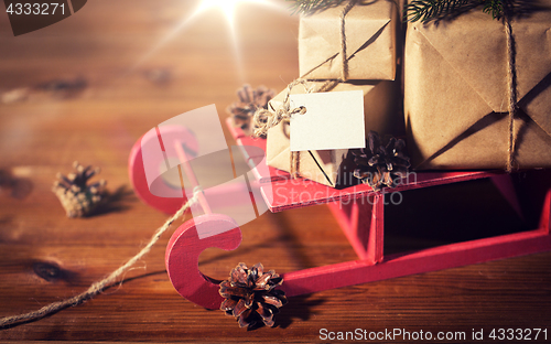 Image of close up of christmas gifts with note on sleigh