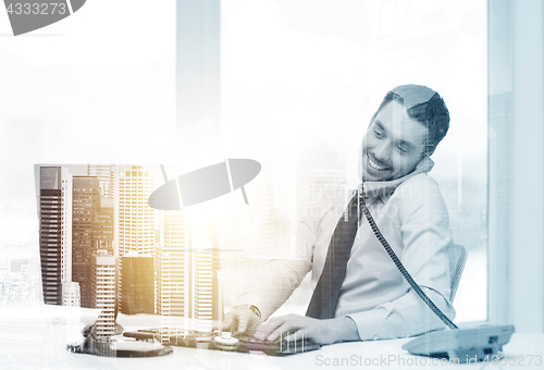 Image of businessman with computer calling phone at office