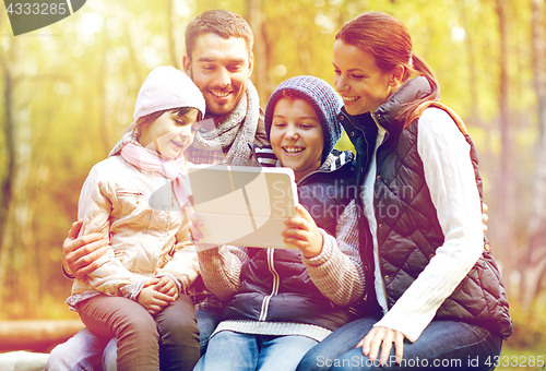 Image of family sitting on bench with tablet pc at camp