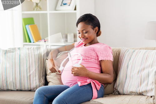 Image of pregnant woman with headphones at home