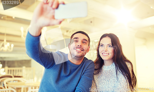 Image of couple taking smartphone selfie at cafe restaurant