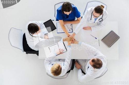 Image of group of doctors holding hands together at table