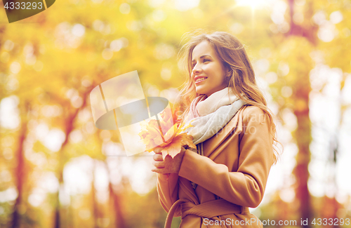 Image of beautiful woman with maple leaves in autumn park