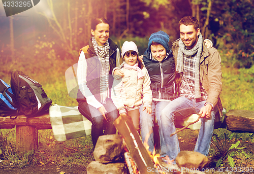 Image of happy family sitting on bench at camp fire