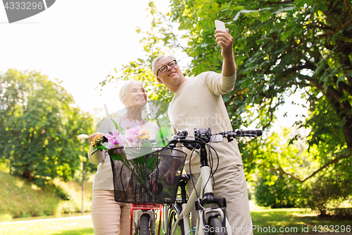 Image of senior couple with bicycles taking selfie at park