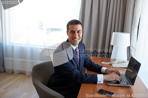 Image of businessman typing on laptop at hotel room