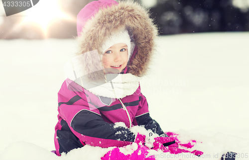 Image of happy kid in winter clothes playing with snow