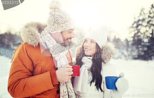 Image of happy couple with tea cups over winter landscape