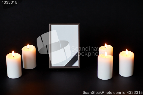 Image of black ribbon on photo frame and candles at funeral