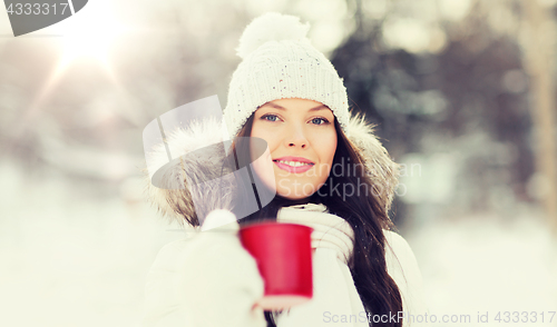 Image of happy young woman with tea cup outdoors in winter