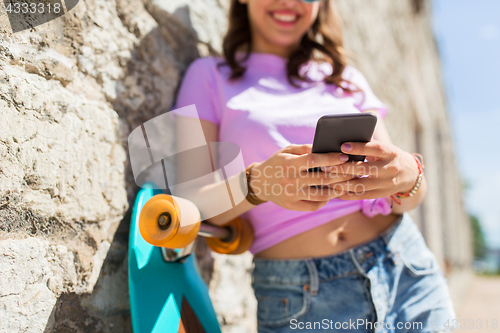 Image of happy teenage girl with longboard and smartphone