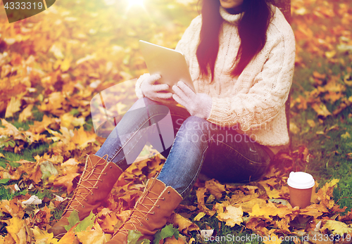 Image of woman with tablet pc and coffee in autumn park