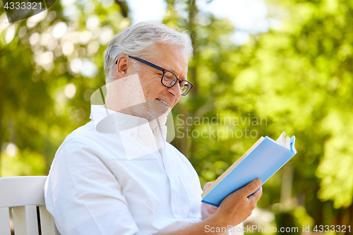 Image of happy senior man reading book at summer park