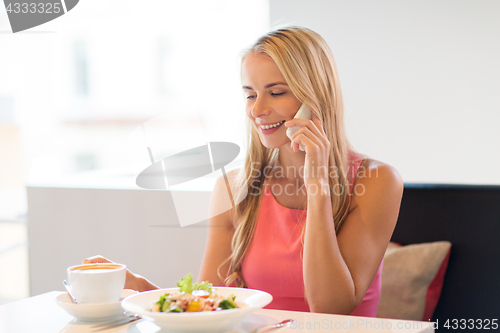 Image of woman with coffee calling smartphone at restaurant