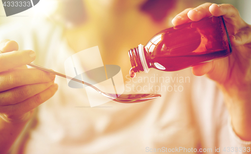 Image of woman pouring medication from bottle to spoon