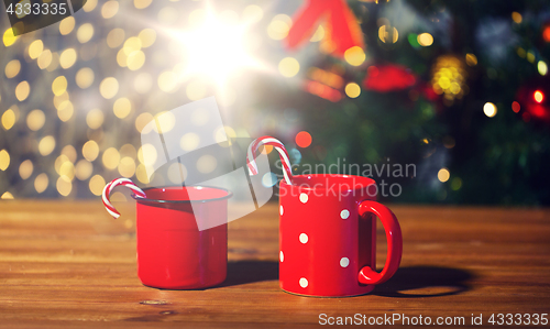 Image of christmas candy canes and cups on wooden table