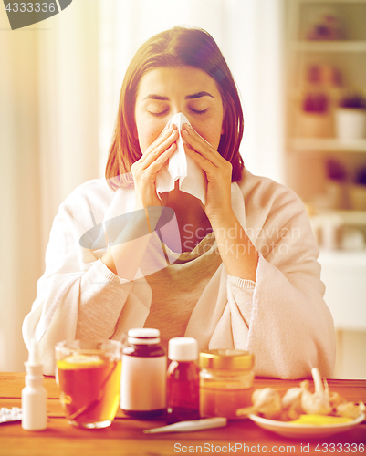 Image of sick woman with medicine blowing nose to wipe