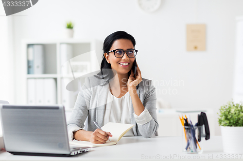 Image of businesswoman calling on smartphone at office
