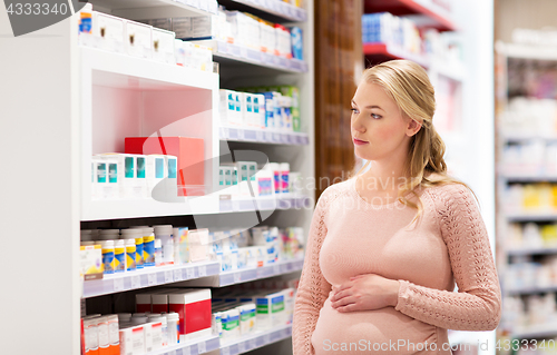 Image of happy pregnant woman with medication at pharmacy