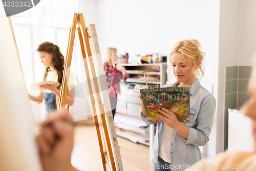 Image of woman artist with easel painting at art school