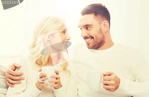 Image of happy couple with cups drinking tea at home