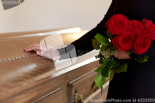 Image of woman with red roses and coffin at funeral