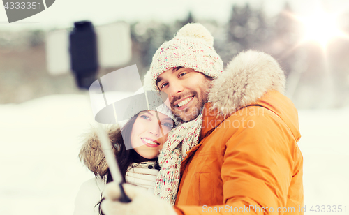 Image of happy couple taking selfie by smartphone in winter