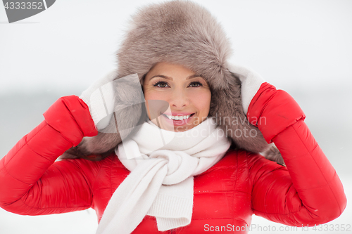 Image of happy smiling woman in winter fur hat outdoors