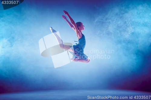 Image of Beautiful young ballet dancer jumping on a lilac background.