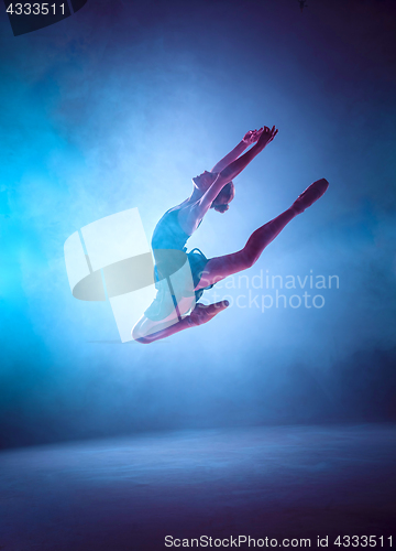 Image of Beautiful young ballet dancer jumping on a lilac background.