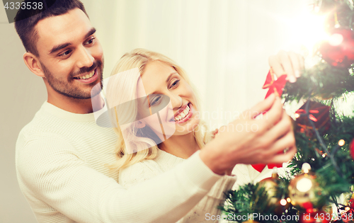 Image of happy couple decorating christmas tree at home