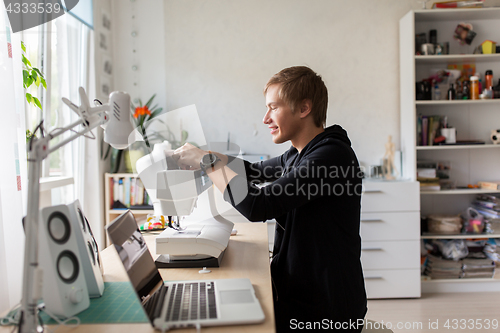 Image of tailor adjusting sewing machine at studio workshop