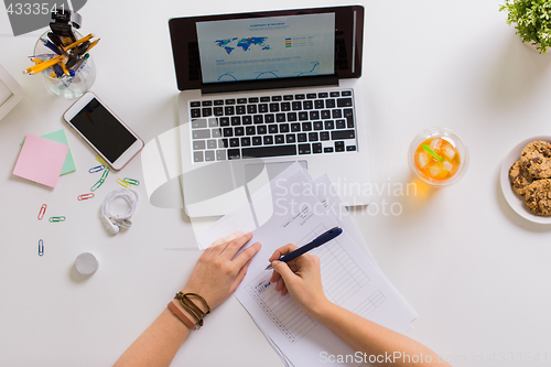 Image of hands with papers and laptop at office table