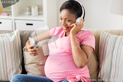 Image of pregnant woman in headphones with smartphone