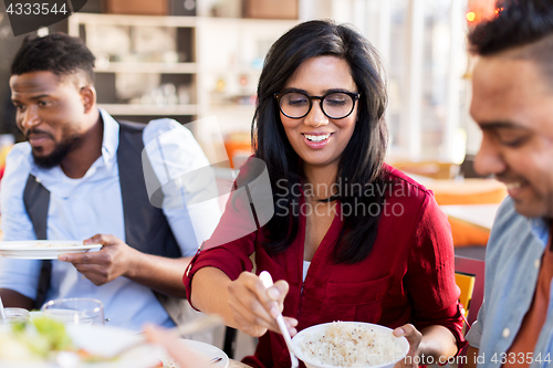 Image of happy friends eating at restaurant