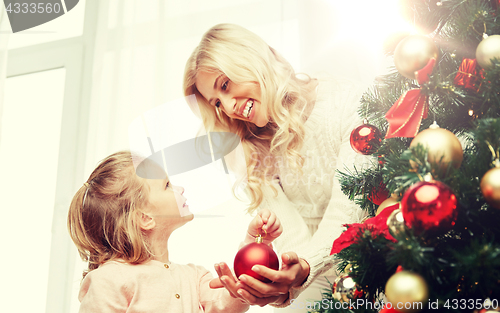 Image of happy family decorating christmas tree at home