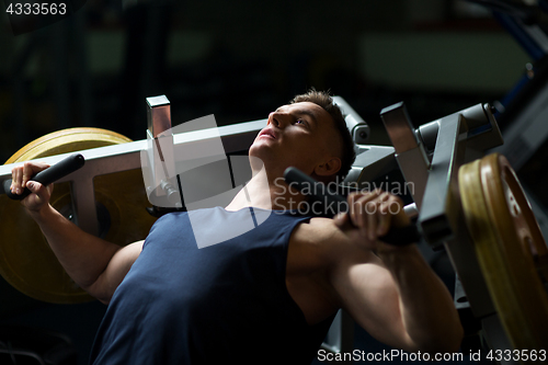 Image of man doing chest press on exercise machine in gym