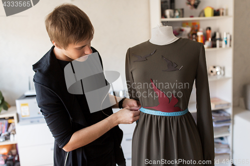 Image of fashion designer with dummy making dress at studio