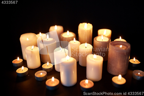 Image of candles burning in darkness over black background