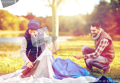 Image of happy father and son setting up tent outdoors