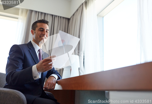 Image of businessman with papers working at hotel room