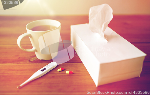 Image of cup of tea, paper wipes and thermometer with pills