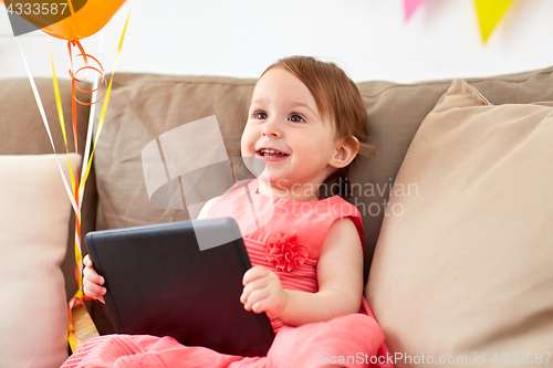 Image of baby girl with tablet pc on birthday party at home