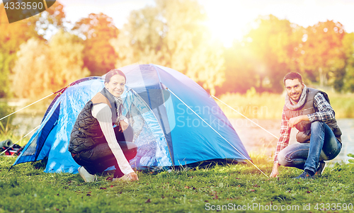 Image of happy couple setting up tent outdoors