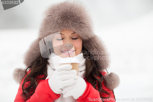 Image of happy woman in winter fur hat with coffee outdoors