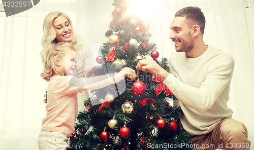 Image of happy family decorating christmas tree at home