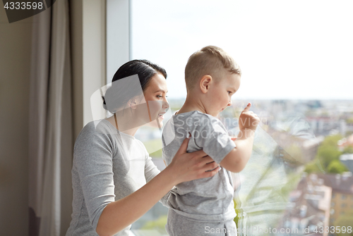 Image of mother and son looking through window at home