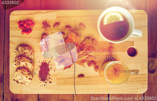 Image of cup of tea with lemon, honey and cookies on board