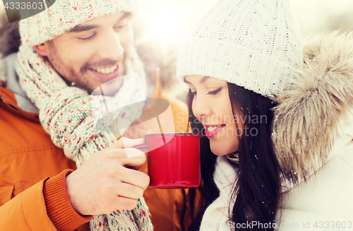 Image of happy couple with tea cups over winter landscape