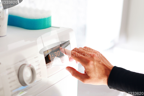 Image of man choosing program for washing machine 